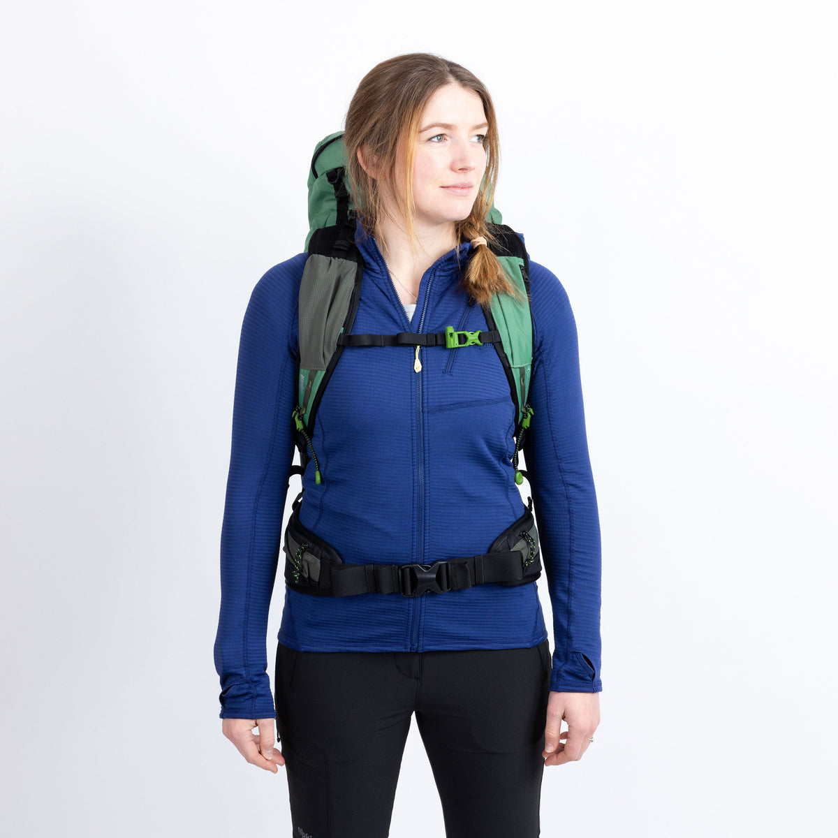Person wearing a blue jacket and green backpack on a white background