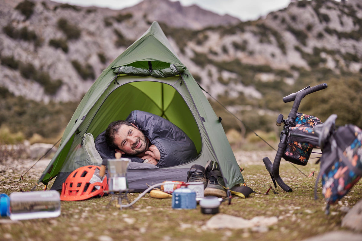 A man sleeping in a bikepacking tent in an ultralight PrimaLoft® sleeping bag - action - closed