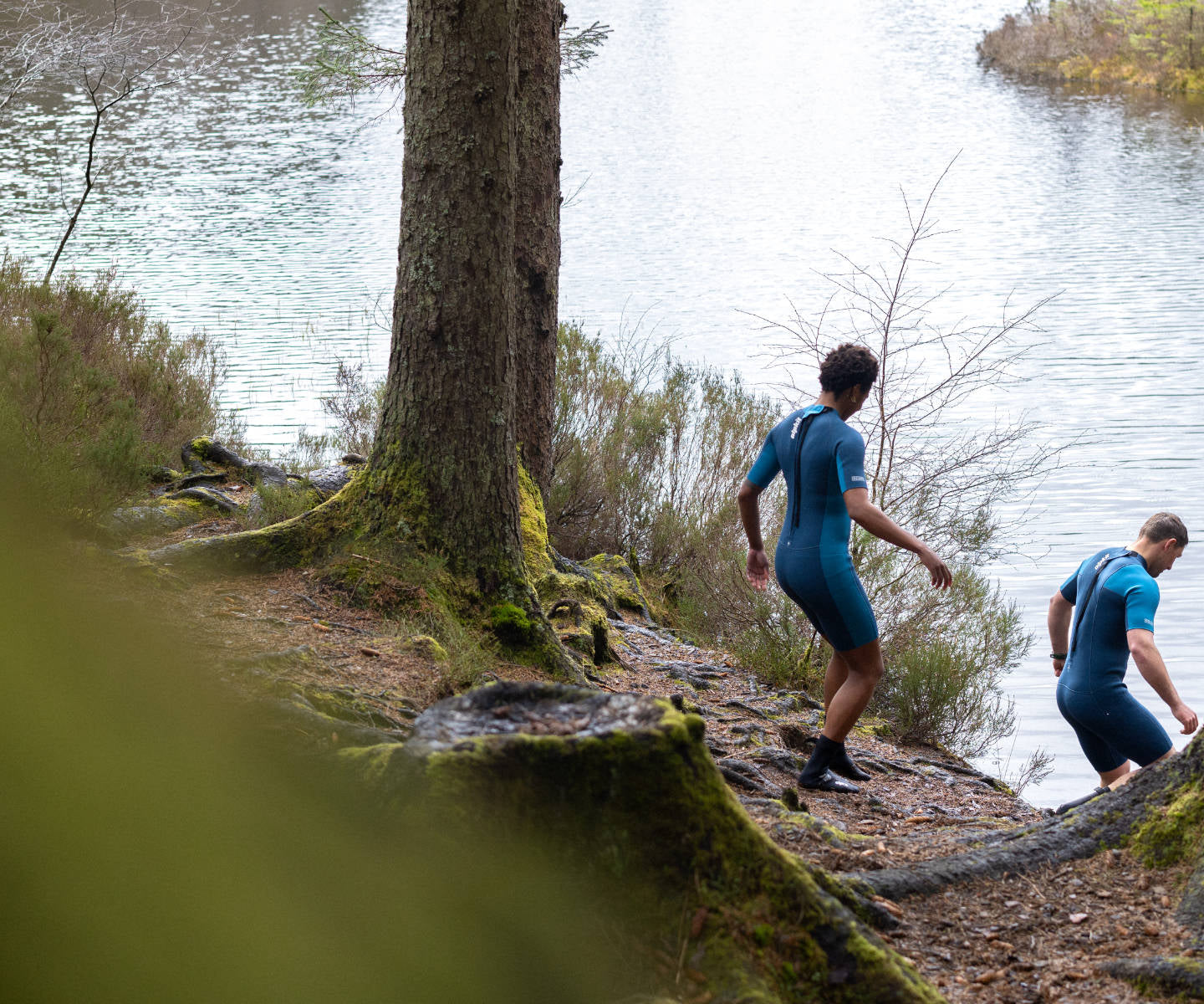 Outdoor swimmers entering the water in wetsuits