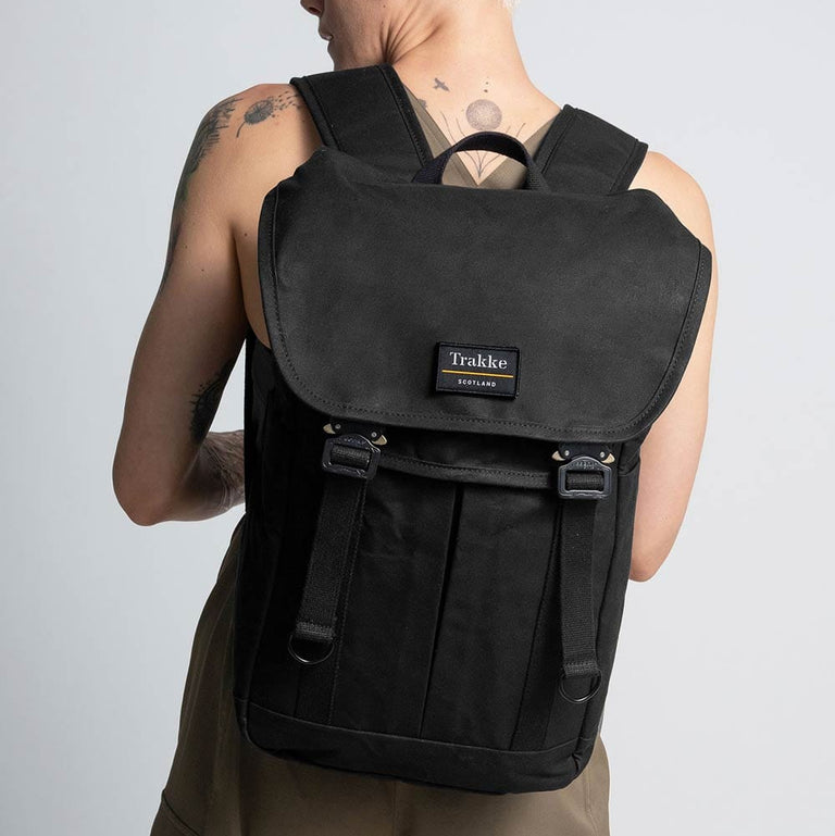 A female model is wearing the Trakke Bannoch Backpack in Black. The Bannoch is the COBRA variant